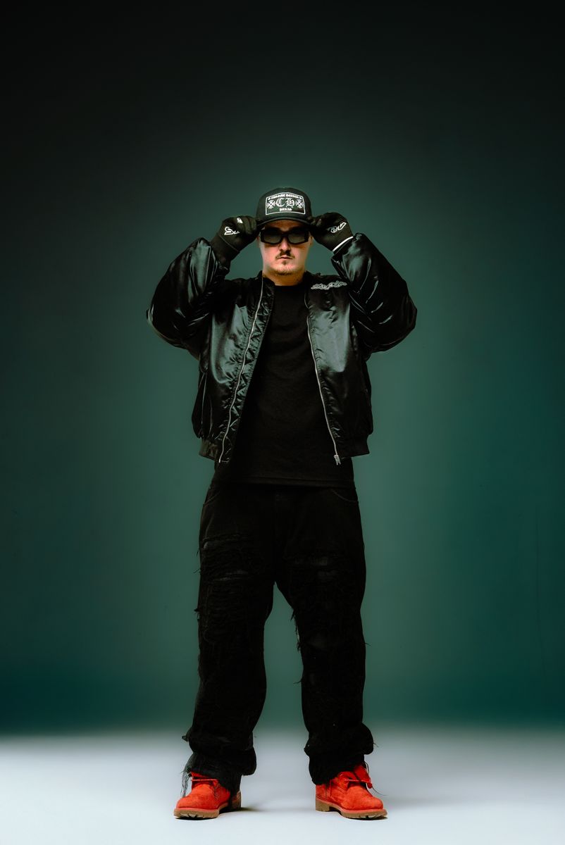Full-length shot of ALVA DJ against a green backdrop