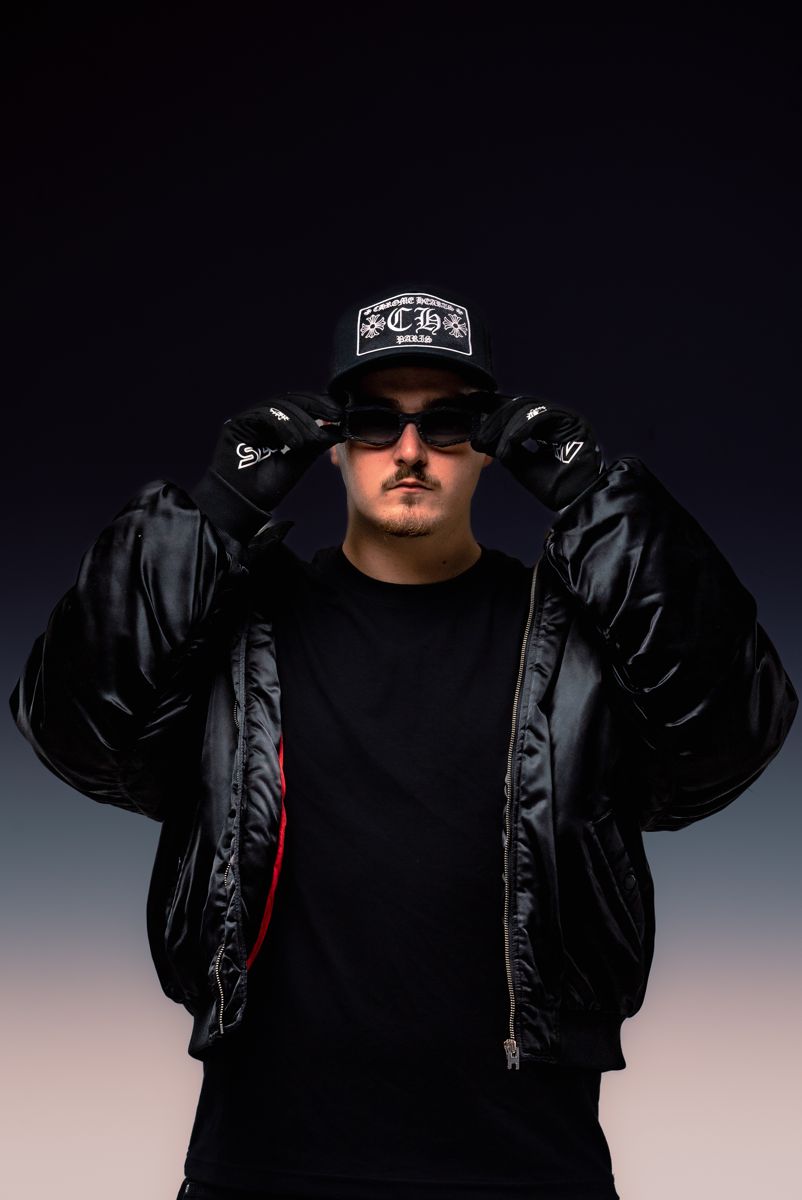 ALVA DJ holding the brim of his cap, wearing a black puffer jacket