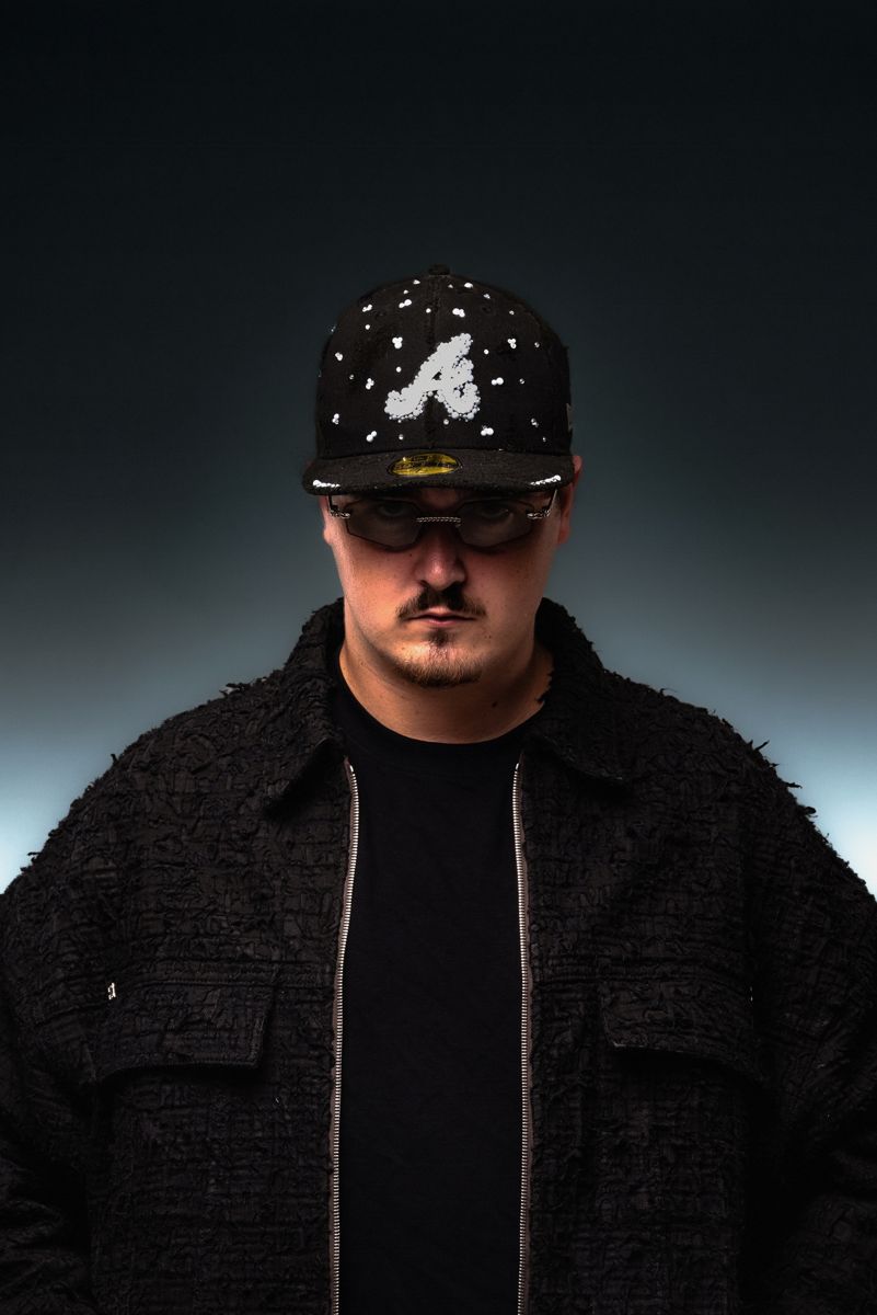 ALVA DJ in a studded cap, head tilted down